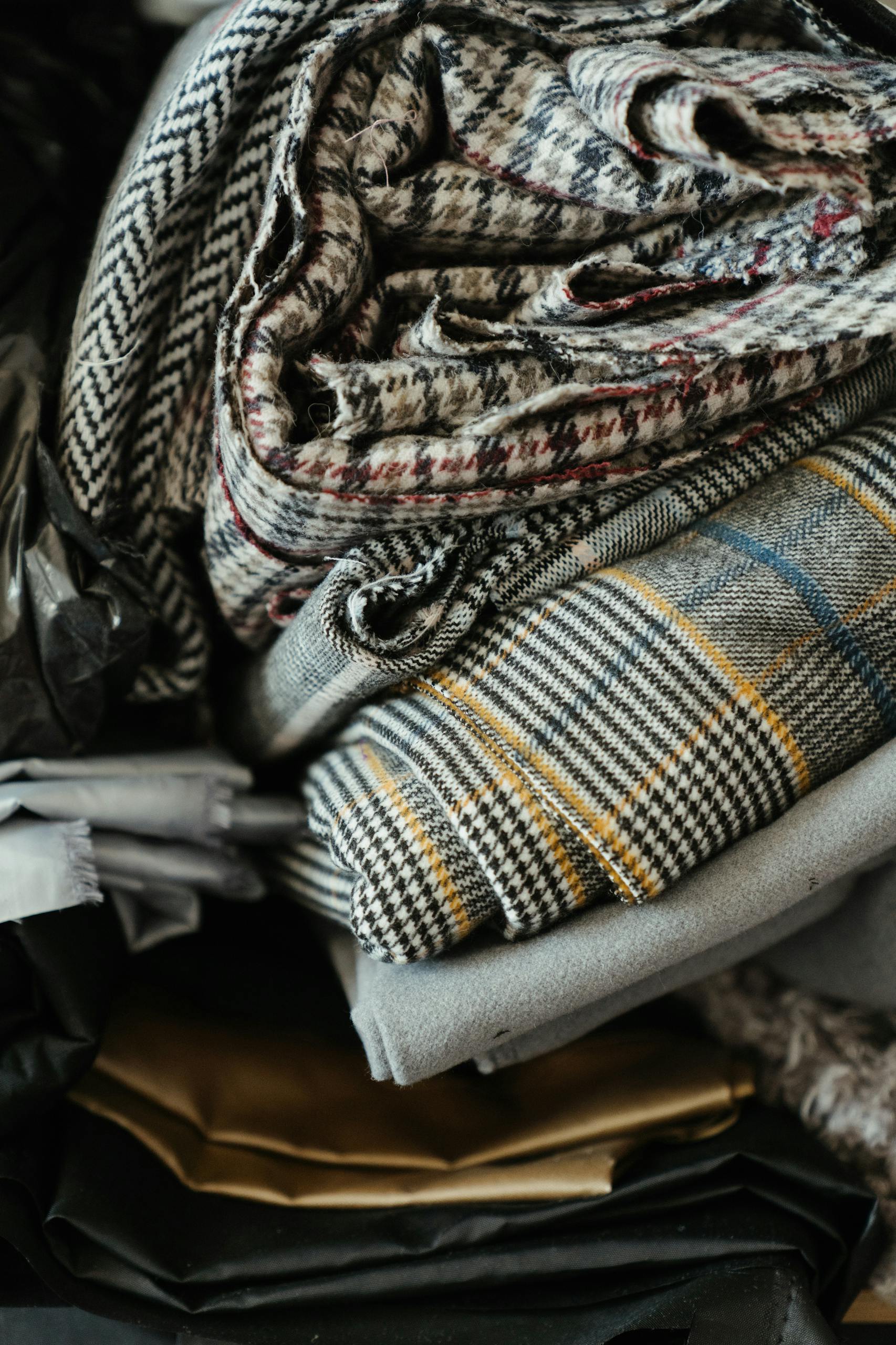 Close-up of folded fabrics showcasing houndstooth and plaid patterns, perfect for textile enthusiasts.
